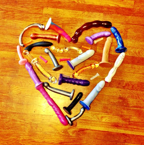 A large heart made out of sex toys on a wooden floor